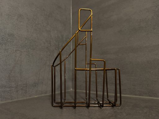 Kunstvolle Treppenstruktur aus Metall in geometrischem Design vor grauem Hintergrund.