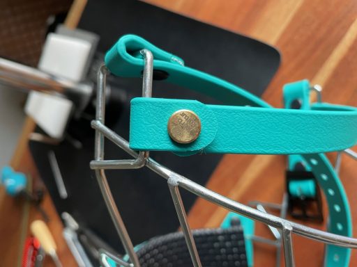 Blauer Haltegurt mit einer Metallknopfverbindung an einem Drahtgestell.